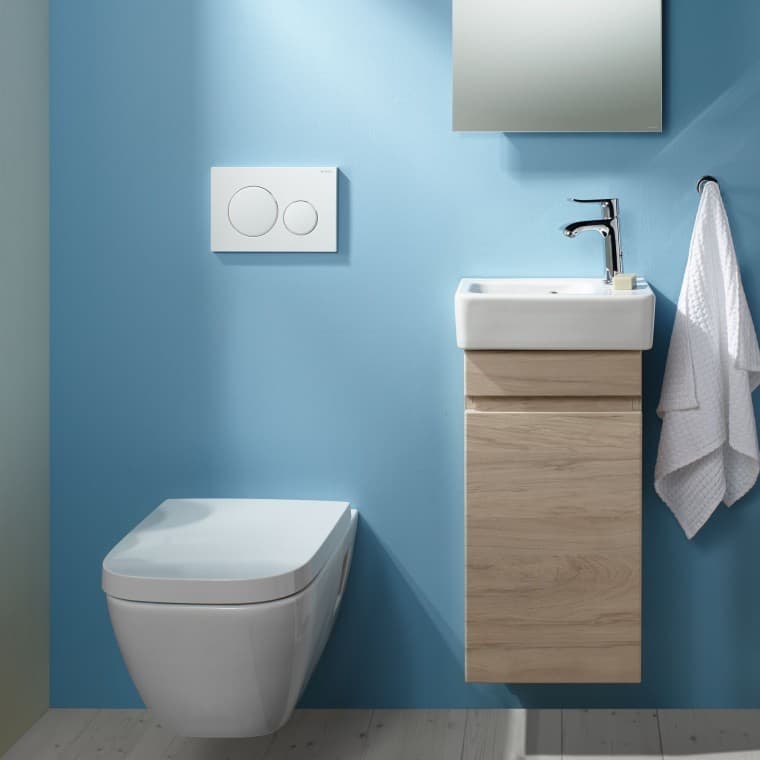An einer hellblauen Wand ist ein wandhängendes Renova Plan WC und ein Waschplatz angebracht An einer hellblauen Wand ist ein wandhängendes Renova Plan WC und ein Waschplatz angebracht