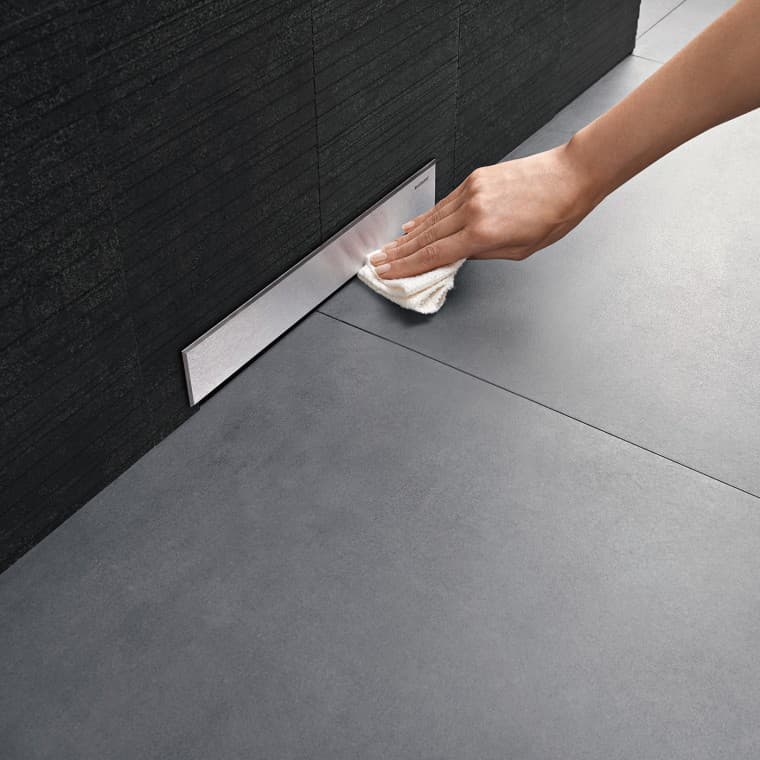 Hand reinigt Blende eines Geberit Wandablaufs Hand reinigt Blende eines Geberit Wandablaufs